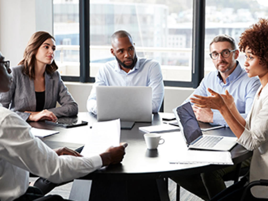 A group of colleagues work at a table in an office