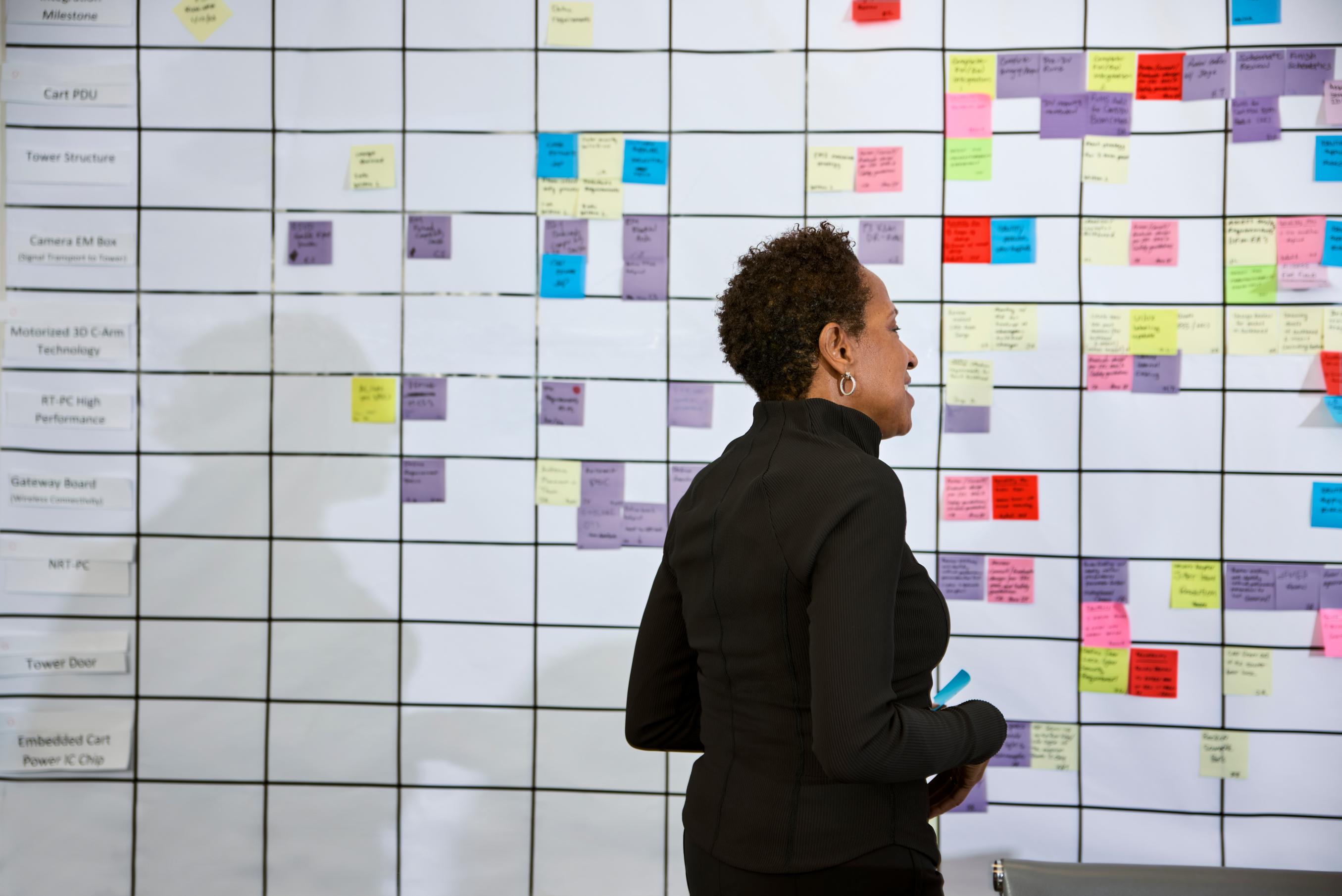 A woman studies a message board at work