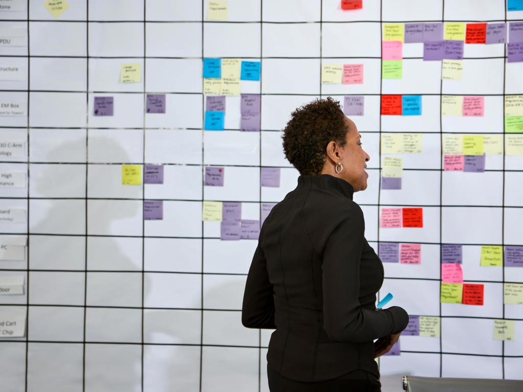 A woman studies a message board at work
