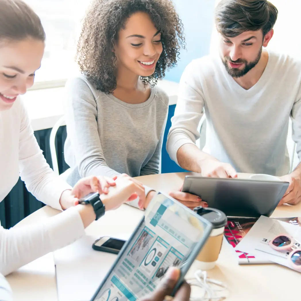 A diverse group of young professionals collaborate on tablets