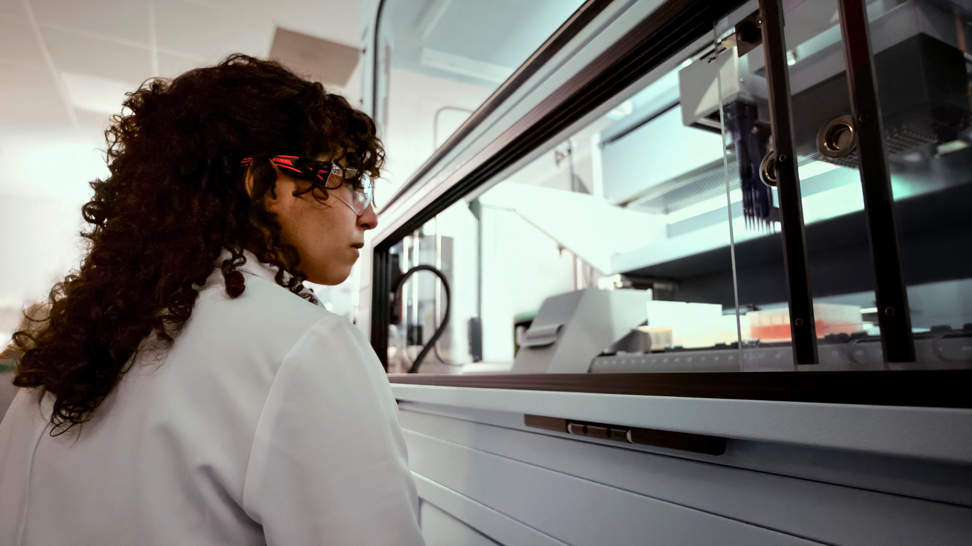 A woman in a white lab coat looks at equipment