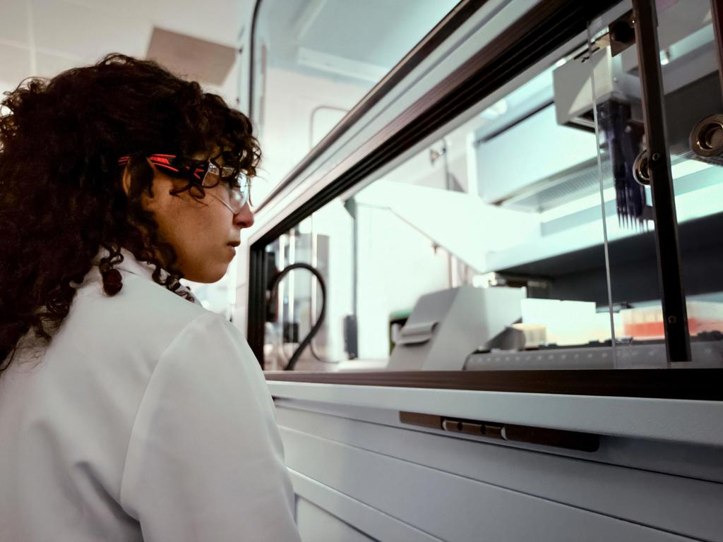A woman in a white lab coat looks at equipment