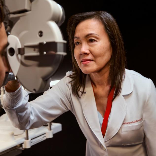 A vision care provider adjusts eye health equipment on a patient.