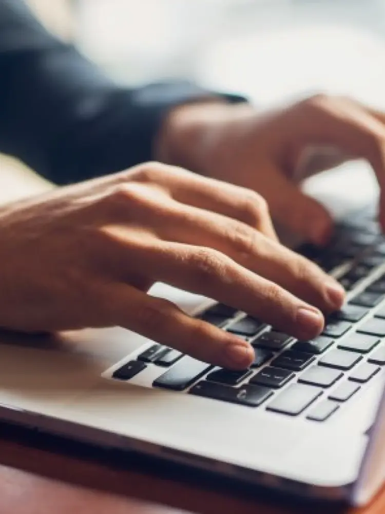 A close up of hands typing on a laptop keyboard