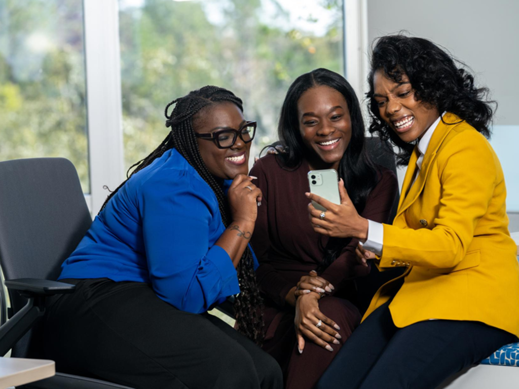 Three women enjoying a laugh while looking at a phone