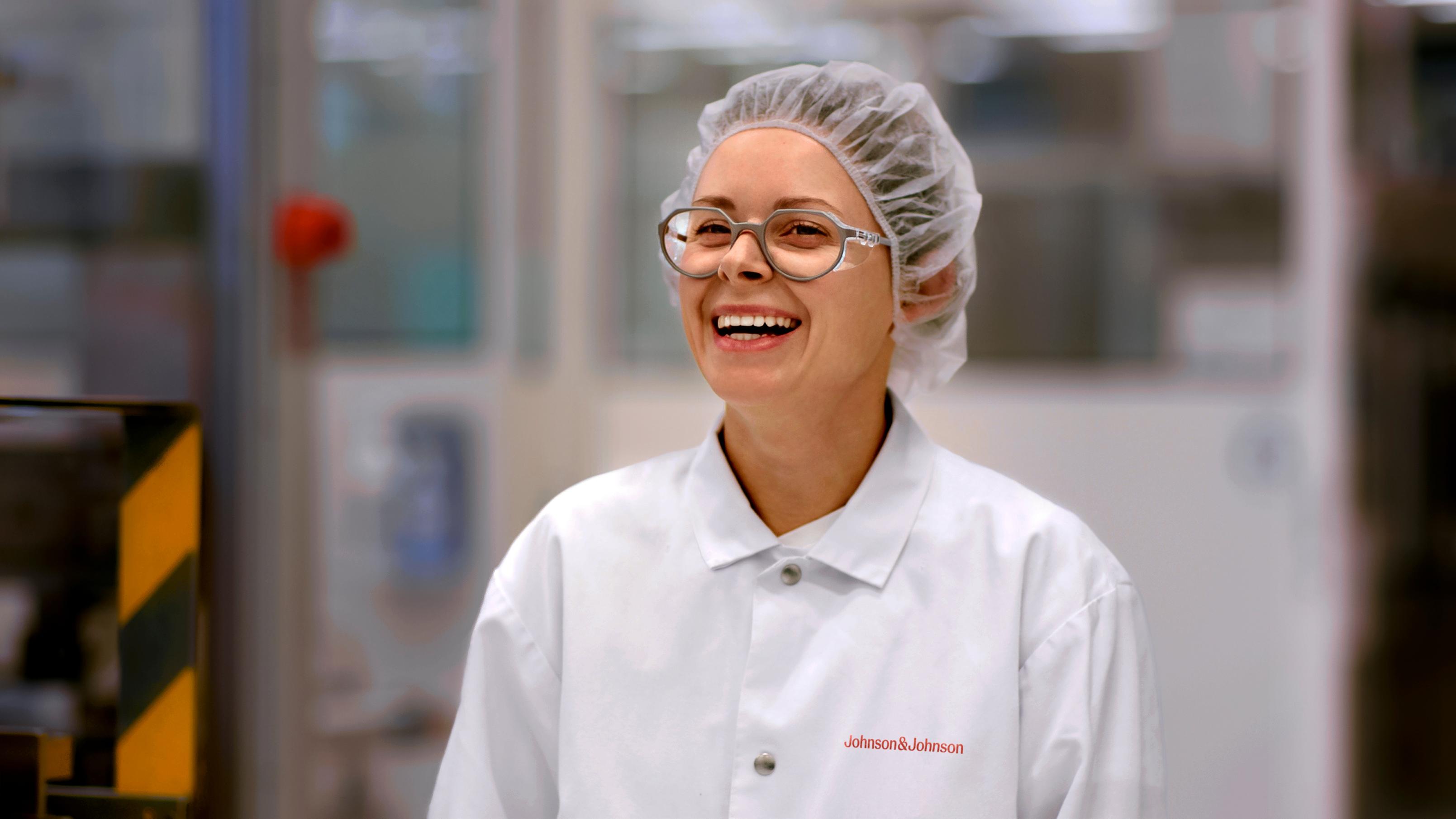 Woman in a white lab coat with protective hair cap in a manufacturing facility
