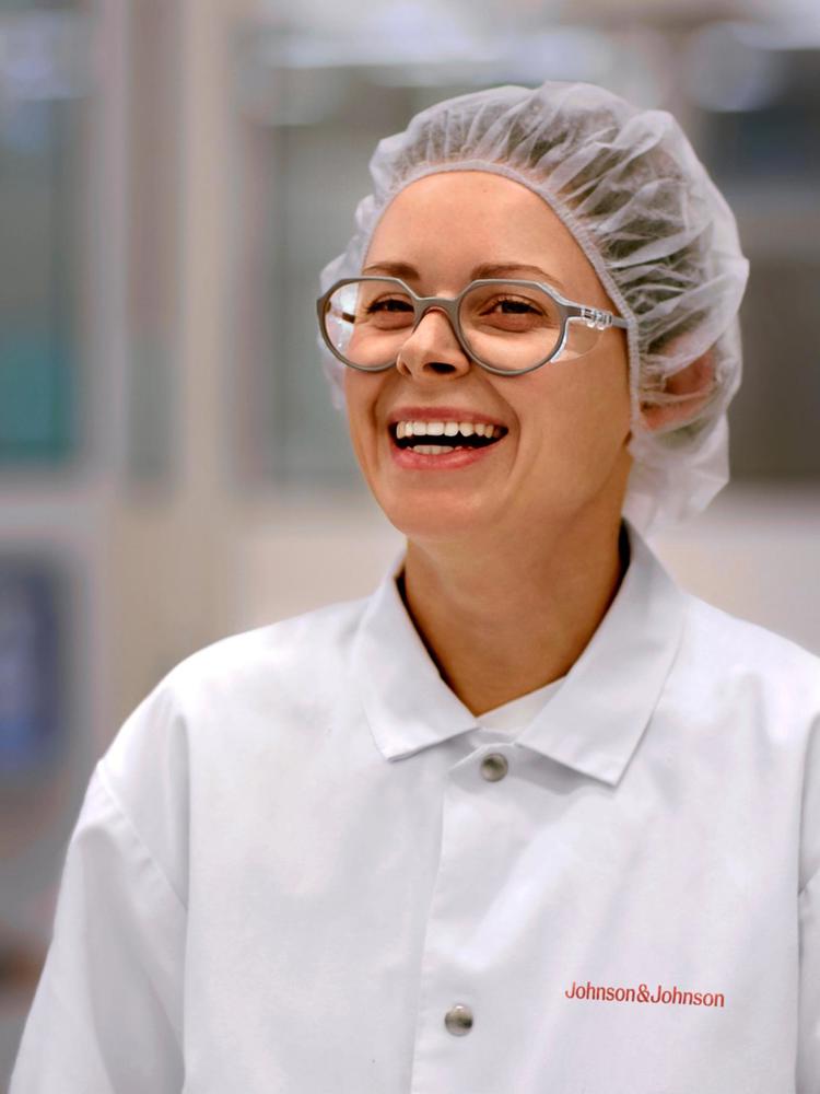Woman in a white lab coat with protective hair cap in a manufacturing facility