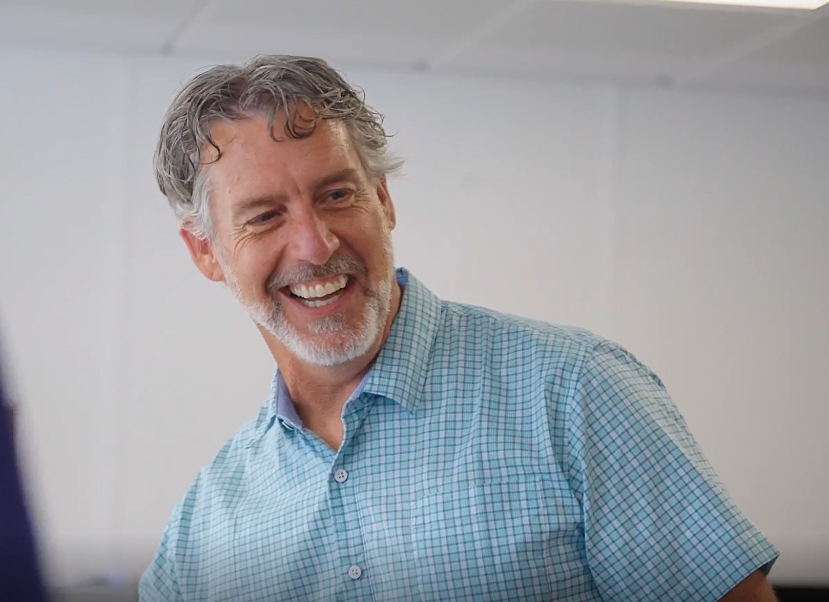 Upper torso portrait of a man smiling wearing a short sleeve blue button down shirt
