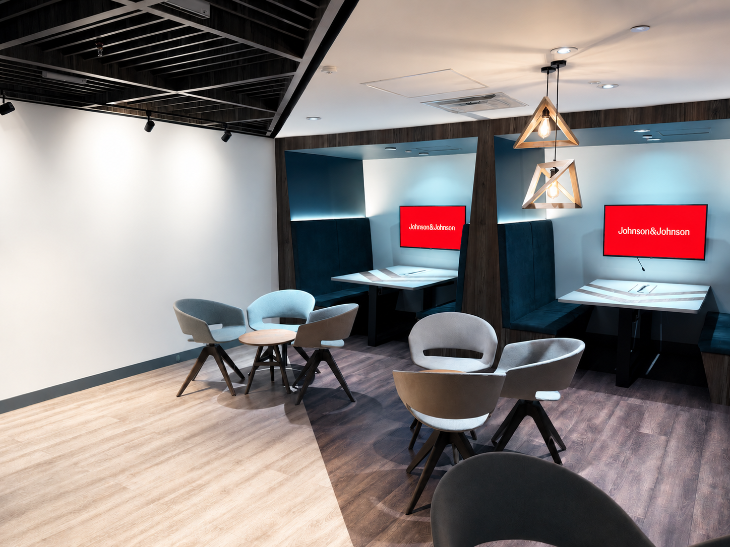 Two desks and a table in a modern collaboration room with J&J logos on the computer screens