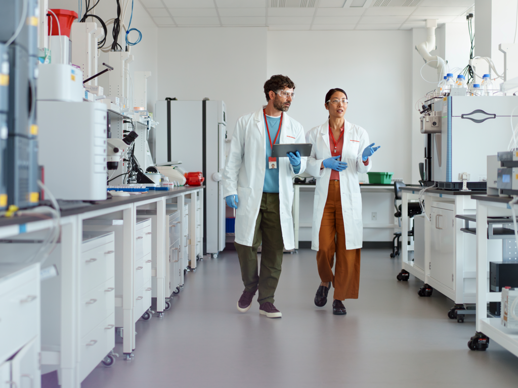 Scientists in discussion and walking through laboratory.