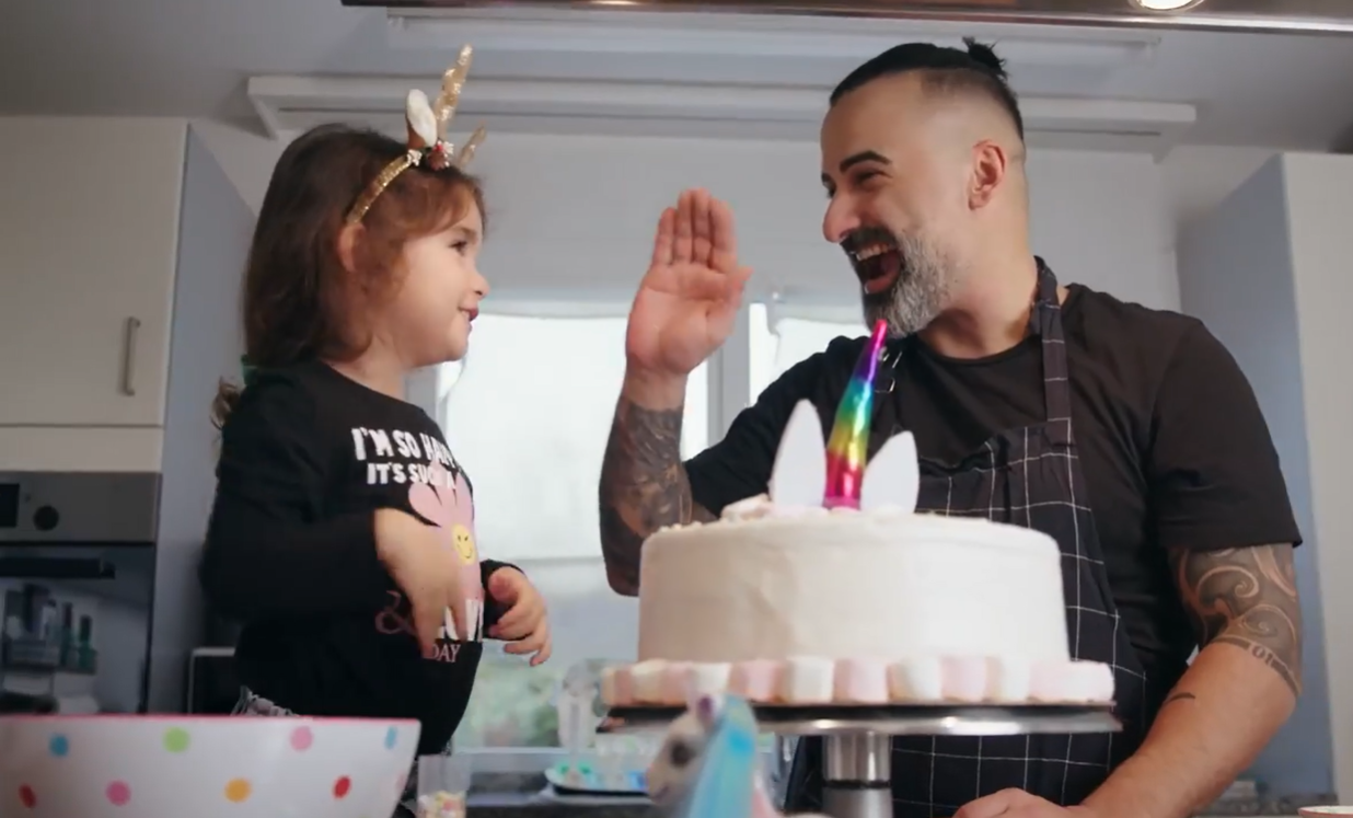 A man and his young daughter laughing over a birthday cake