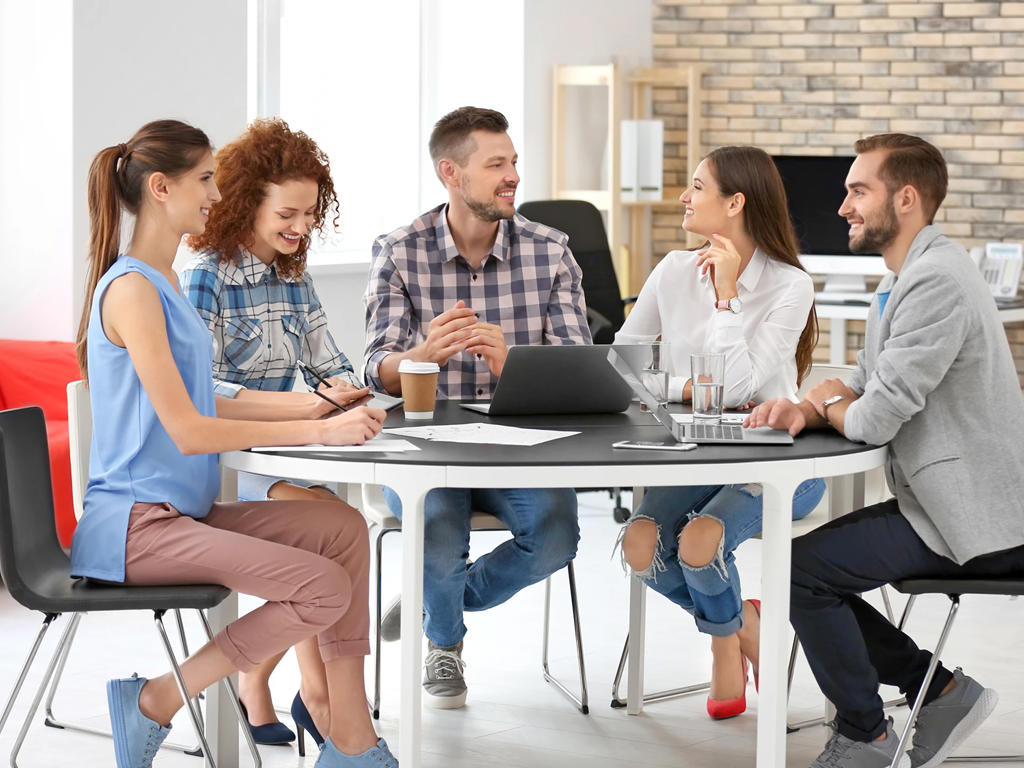A group of young professionals sit around a table in an office