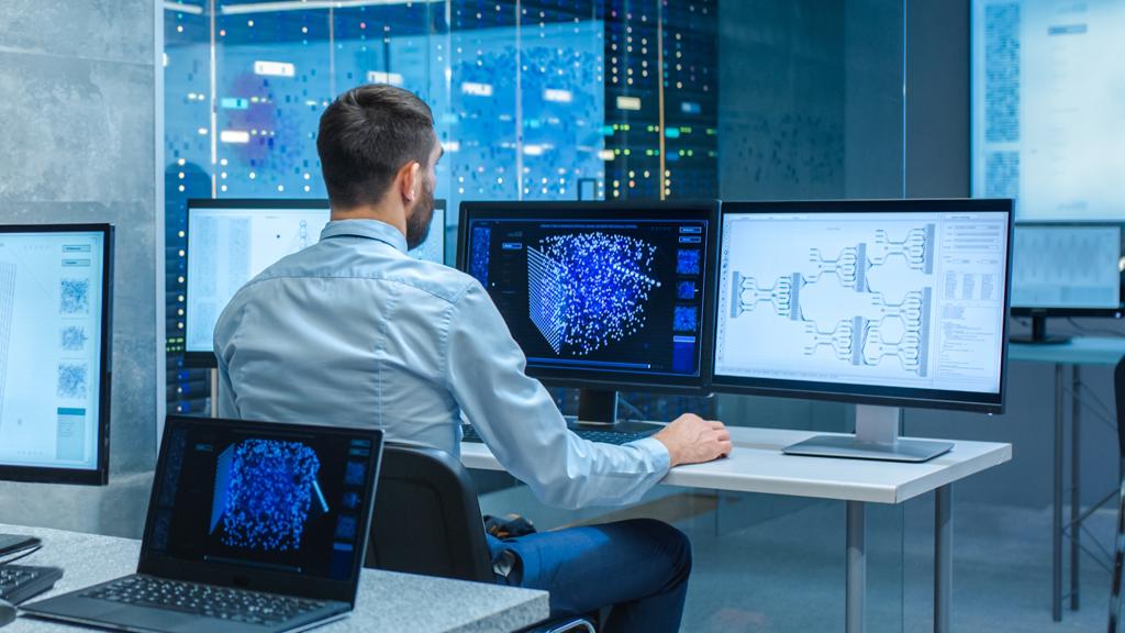 JJ Photo Man Sitting At Desk Working On Multiple Displays Shutterstock 1538502419