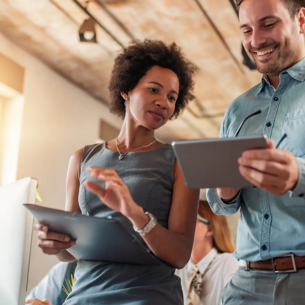 A man and woman collaborating while holding tablets