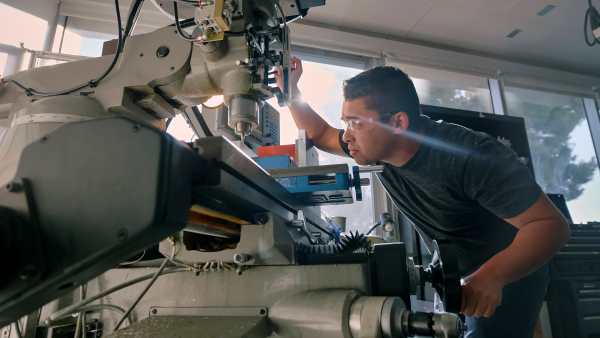 Low-angle close view inside a machine shop showing a person operating a machine.