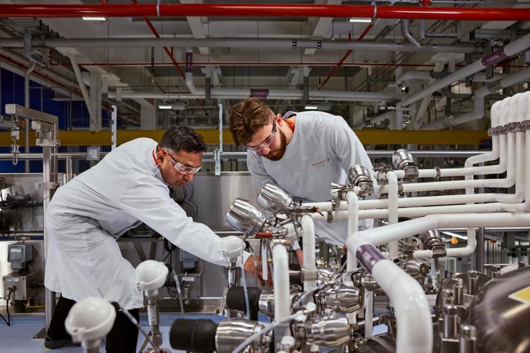 Two J&J employees troubleshooting complex machinery in a manufacturing environment