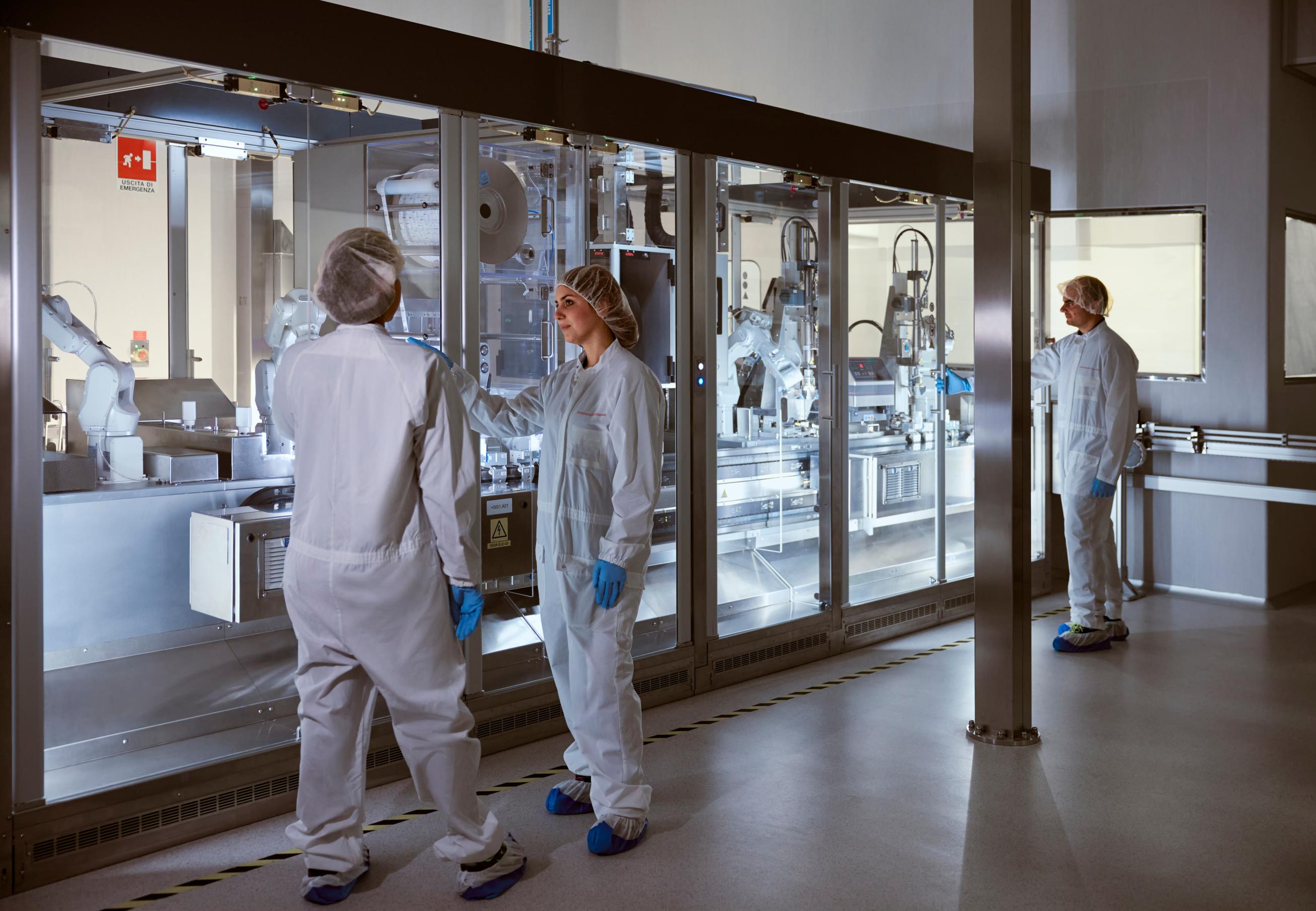 A pharmaceutical packaging area where two operations supervisors are standing in front of an automated packaging line,