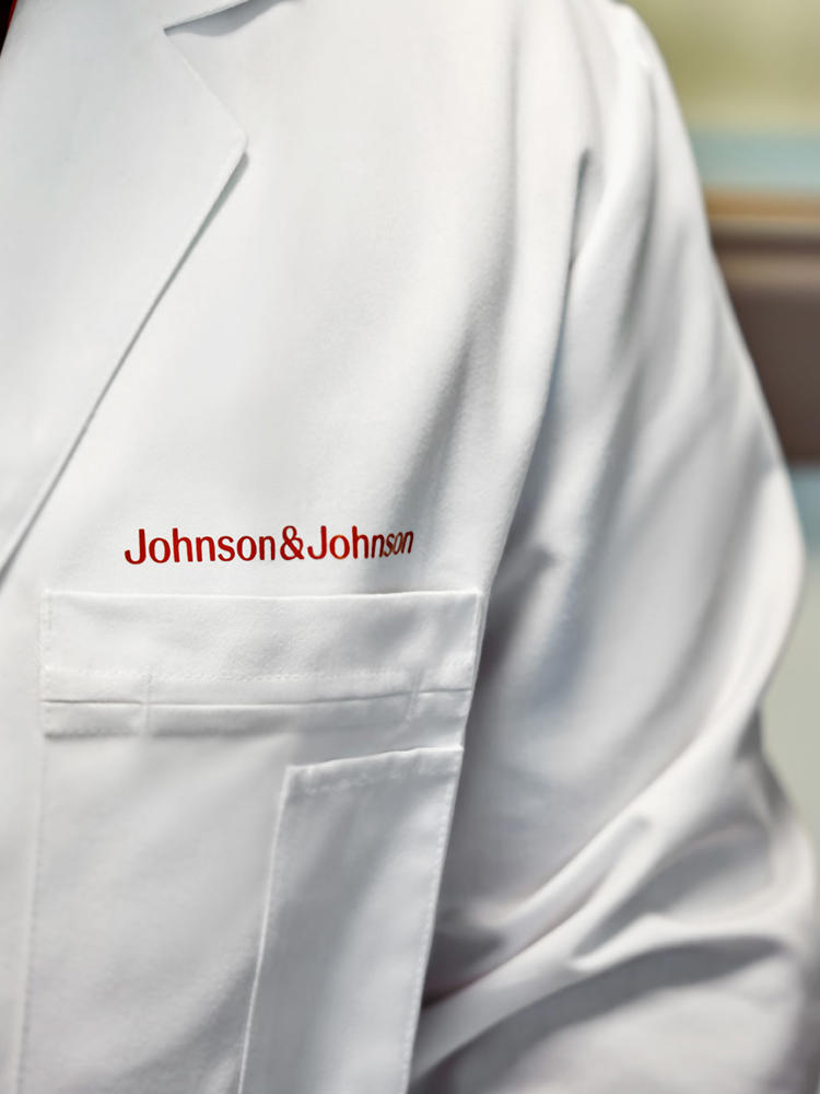 A close up of a person wearing a white lab coat with Johnson & Johnson logo