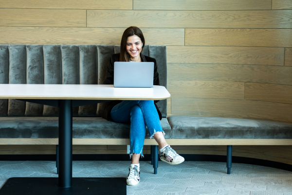 A woman sitting at a laptop smiling preparing for an interview