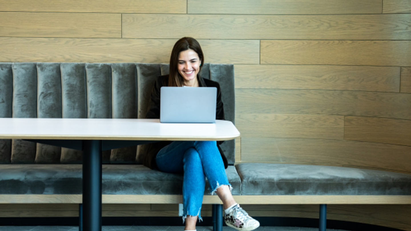 A woman sitting at a laptop smiling preparing for an interview