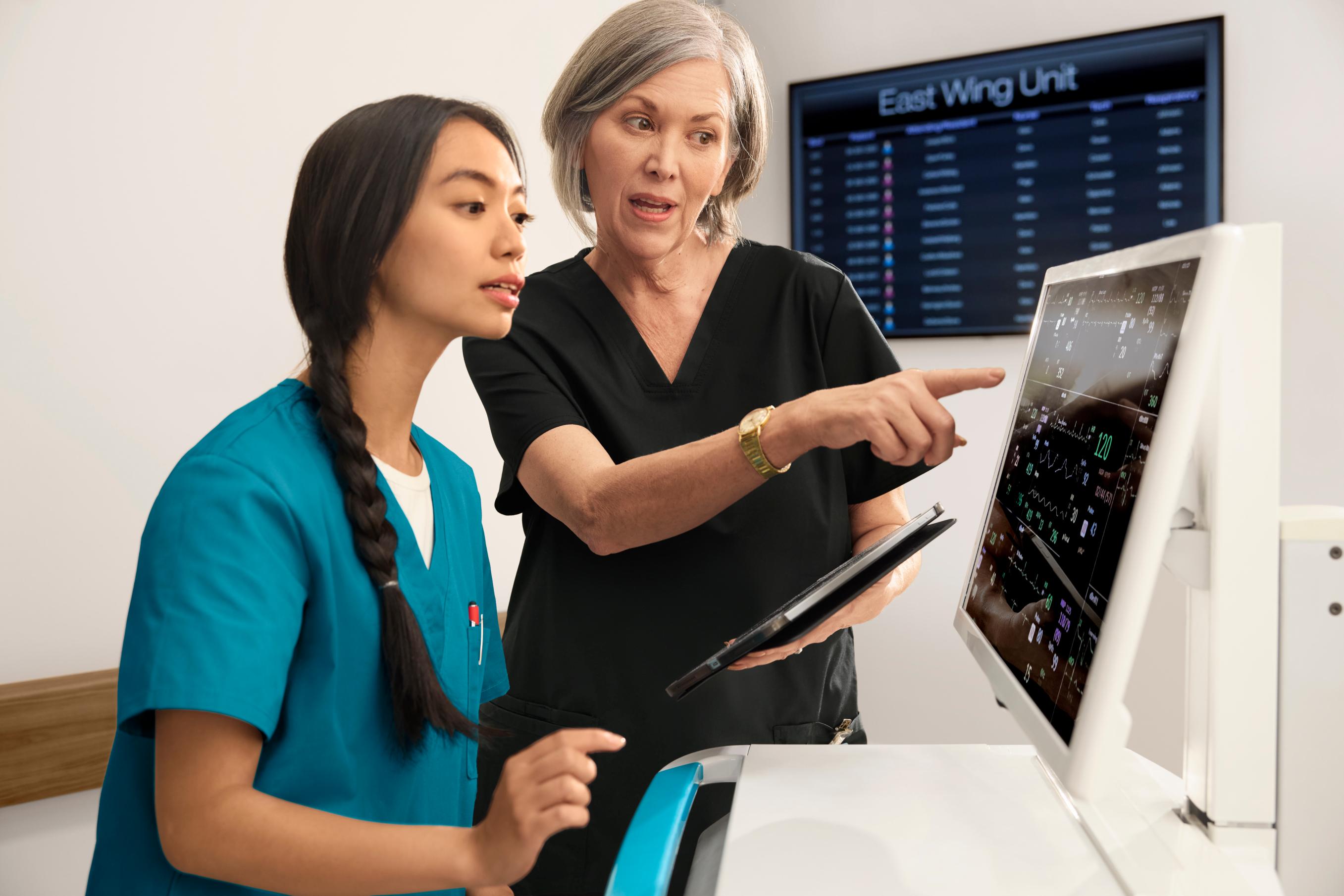 Two women look at patient data in a hospital