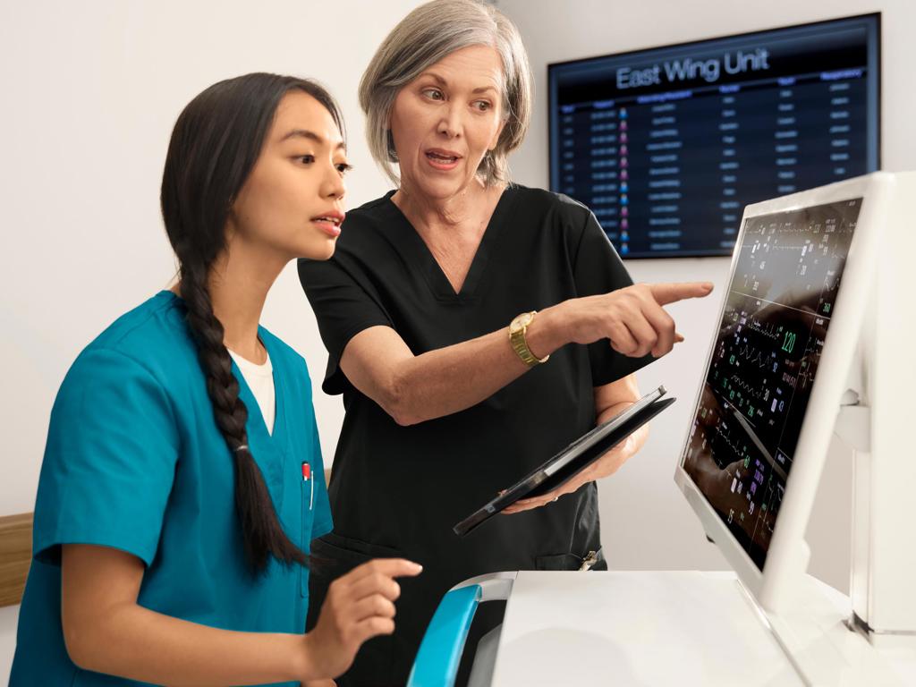 Two women look at patient data in a hospital