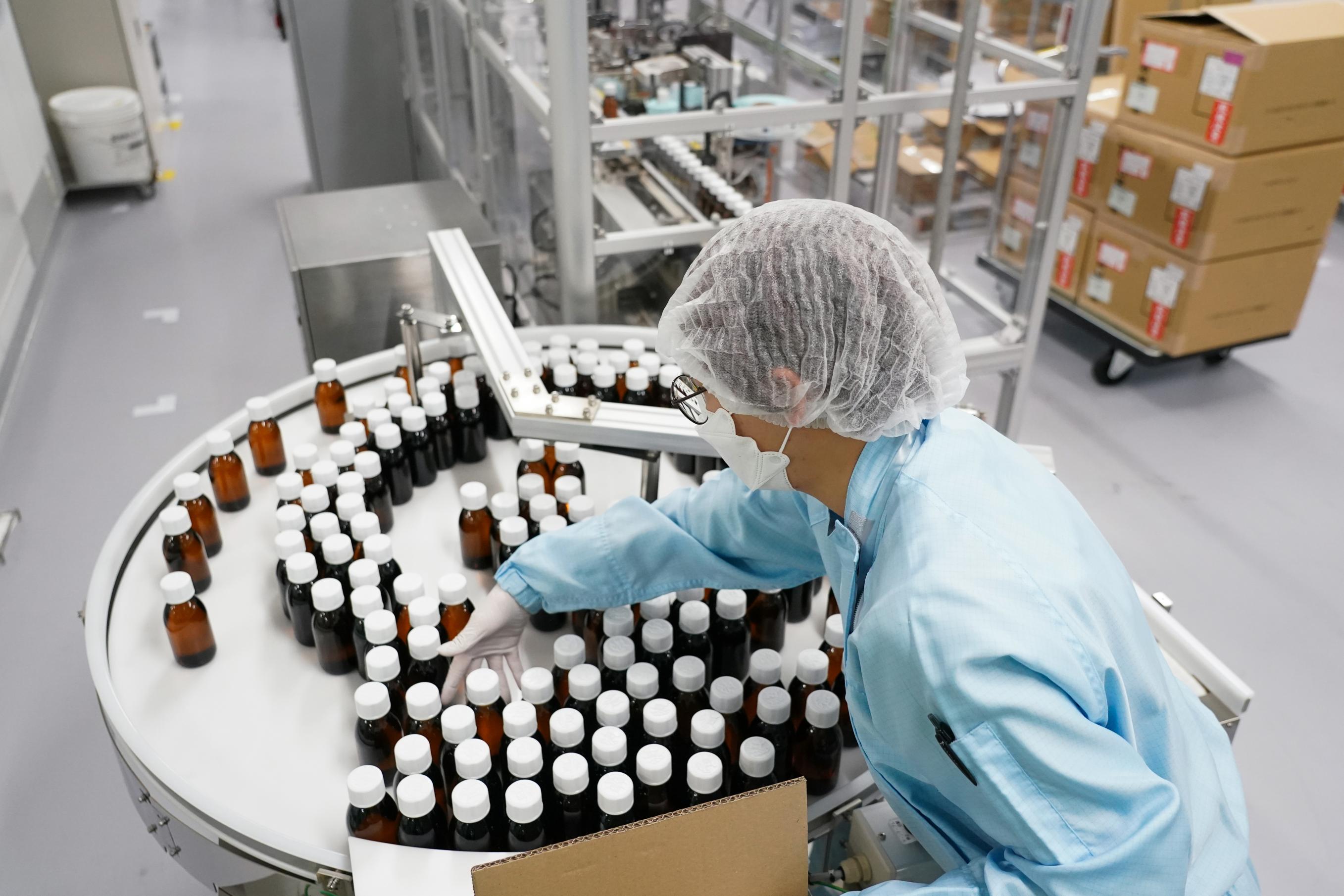 A worker in protective gear sorts bottles for boxing