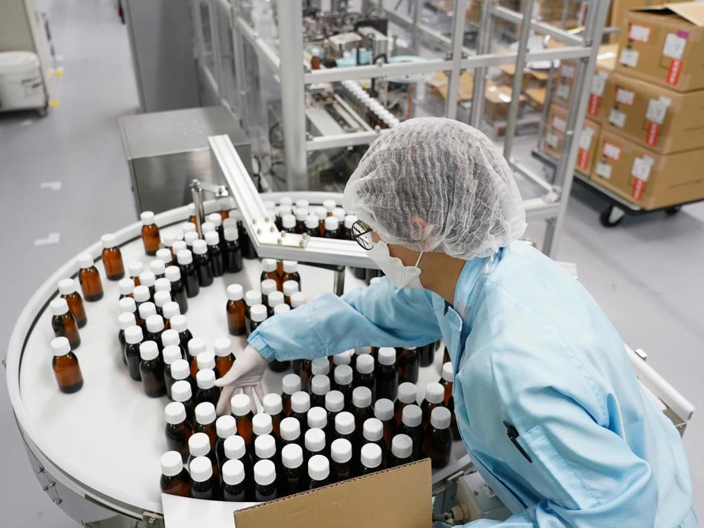 A worker in protective gear sorts bottles for boxing